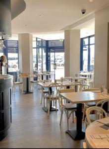 a restaurant with wooden tables and chairs and windows at Hotel Le Richelieu in Le Tréport