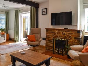 uma sala de estar com uma lareira de tijolos e uma televisão de ecrã plano em Why Not em Canterbury