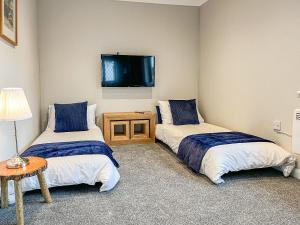 duas camas num quarto com uma televisão na parede em Havre De Calme em Halstead
