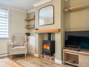 a living room with a wood stove and a mirror at The Snug in Southwell