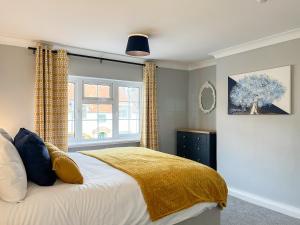 a bedroom with a bed with a yellow blanket and a window at The Snug in Southwell