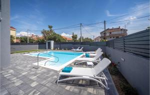 a swimming pool with white lounge chairs next to a fence at Villa Bibinje in Bibinje