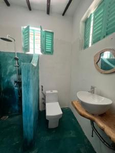 a bathroom with a white toilet and a sink at Duara Beach House in Paje