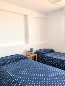 twee bedden in een kamer met blauwe polka dot lakens bij Ático con vistas al mar in Punta Umbría
