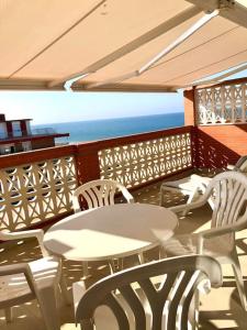 a balcony with white tables and chairs and the ocean at Ático con vistas al mar in Punta Umbría +8 photos