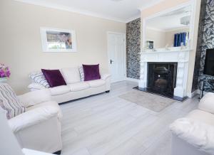 uma sala de estar com dois sofás brancos e uma lareira em Ballygarrett Holiday Home em Ballygarrett