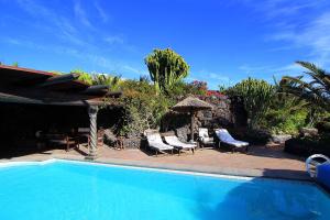 einen Pool mit 2 Stühlen und einem Sonnenschirm in der Unterkunft Casa La Concha in La Asomada