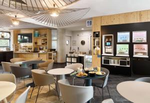 un restaurante con mesas y sillas y una cocina en B&B HOTEL Vélizy Est, en Vélizy-Villacoublay