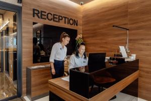 two women standing at a reception desk in a restaurant at Garni Hotel Kruso in Herceg-Novi