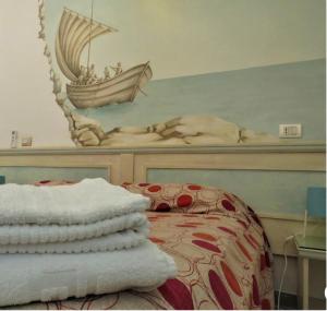 a bedroom with a bed with a painting of a boat at Sunset le Sirene in Scilla