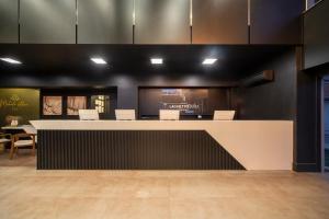 a lobby with a counter with chairs and a table at Hotel Laghetto Stilo Borges in Gramado