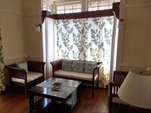 - un salon avec un canapé, une table et une fenêtre dans l'établissement Cafe Shillong Bed and Breakfast, à Shillong