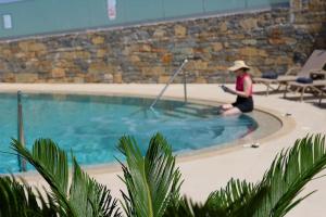 a woman in a hat sitting in a swimming pool at Modern Family apartment Ewa with pool, dining area on Crete coast in Stavromenos