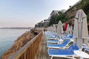 eine Reihe von Liegestühlen mit Sonnenschirmen auf einem Pier in der Unterkunft Ramada Plaza Antalya in Antalya