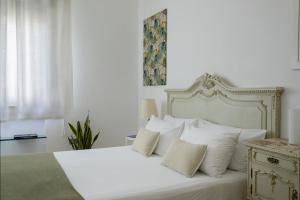 a bedroom with a white bed with white pillows at Le case di Frelli in Palermo +25 photos