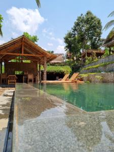 a swimming pool with a wooden pavilion and water at Tetebatu Sama Sama Bungalows in Tetebatu