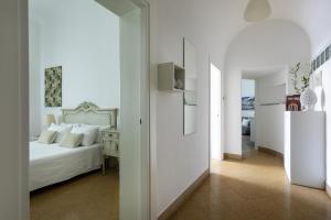 a white bedroom with a bed and a hallway at Le case di Frelli in Palermo