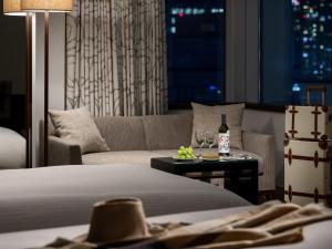 a hotel room with a bed and a couch with wine glasses at Hotel The Celestine Tokyo Shiba in Tokyo