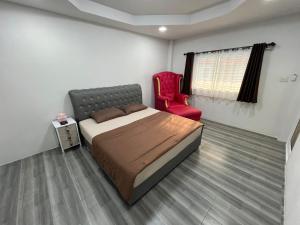 um quarto com uma cama e uma cadeira vermelha em Nuttida resort ณัฐธิดา รีสอร์ท em Ban Khae Taphao