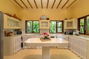 a large kitchen with a table and some windows at Allamanda Villa by YourHost, 10 bedroom, Malindi in Malindi