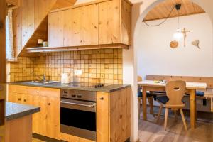 una cocina con armarios de madera y una mesa con comedor. en Ronacherhof Apt Ringelblume, en Auna di Sopra