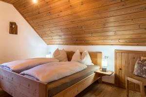 Cama en habitación con techo de madera en Ronacherhof Apt Ringelblume, en Auna di Sopra