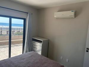 1 Schlafzimmer mit einem Bett und einem Fenster mit Klimaanlage in der Unterkunft APARTAMENTO FRENTE MAR in Itapema