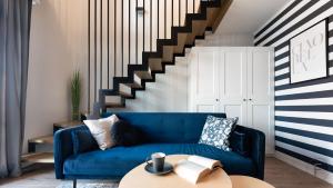 a living room with a blue couch and stairs at Flatbook - City Center SPA Apartments Dwie Motlawy in Gdańsk