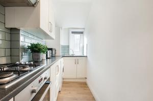 a kitchen with white cabinets and a counter top at London Paddington Station Apartments in London