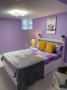 ein lila Schlafzimmer mit einem Bett mit gelben Kissen in der Unterkunft Sweet Home with beautiful ambiance 2 bedroom in Brampton