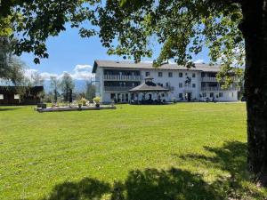 a large white building with a large field of grass at Hotel Fuchs & Hase SELF CHECK IN in Rosegg