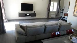 een woonkamer met een bank en een flatscreen-tv bij Charmante villa d.Architecte 200m2 à 20 min de la mer in Saint-Geniès-de-Fontedit