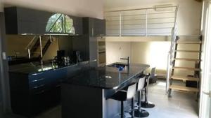 een keuken met een zwart aanrecht en wat krukken bij Charmante villa d.Architecte 200m2 à 20 min de la mer in Saint-Geniès-de-Fontedit