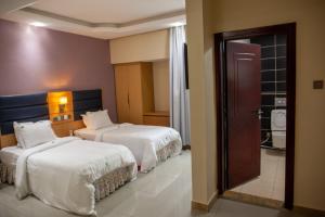 ein Hotelzimmer mit 2 Betten und einer Tür in der Unterkunft HOTEL MICKEL in Douala