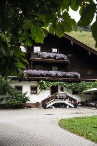 a building with a balcony with purple flowers on it at Hochwart Hof Bed & Breakfast in Saalbach Hinterglemm +17 photos