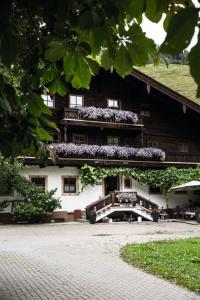 a building with a balcony with purple flowers on it at Pension Hochwart Hof in Saalbach-Hinterglemm