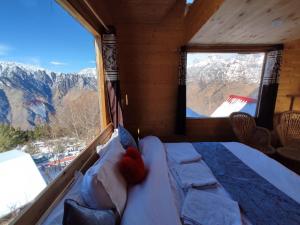 a bedroom with a bed and a large window at Poppy Resorts Auli in Joshīmath