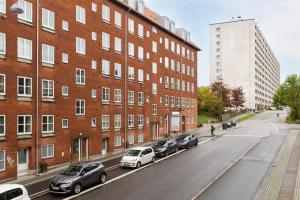 a row of cars parked next to a brick building at 400 meter til Åen - Moderne og fuldt udstyret in Aarhus