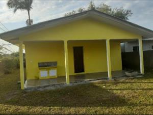 una pequeña casa amarilla con porche en Praiana en Guaratuba