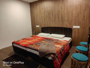 a bedroom with a bed and two stools in it at Auli Eco Nature Resort in Joshīmath