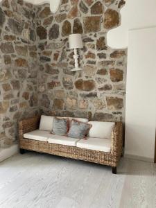 een rieten bank in een kamer met een stenen muur bij Golden rooms in Castellammare di Stabia