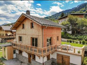 a large wooden house with a large deck at Chalet cosy et confortable in Savoie