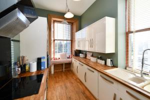 a kitchen with green walls and white cabinets and a sink at Pladda View in Ayr