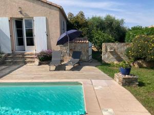 a pool with two chairs and an umbrella next to a house at Chez Liselotte in Borgo