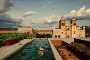 a person swimming in a pool in front of a building at Otro Oaxaca, a Member of Design Hotels in Oaxaca City