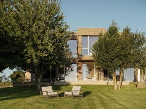 a house with two chairs and two trees in the yard at Hotel Amiuka in O Pedrouzo