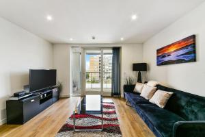 a living room with a black couch and a tv at Amazing 2 bed 2 bath flat in Canary Wharf in London