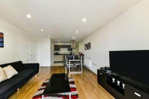 a living room with a black couch and a kitchen at Amazing 2 bed 2 bath flat in Canary Wharf in London