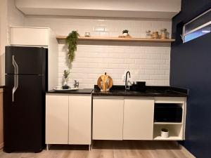 a kitchen with white cabinets and a black refrigerator at Apê Brooklin -Berrini in Sao Paulo