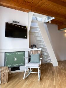 a white chair in a room with a tv and stairs at Mansarda Bel Panorama in Villa dʼAllegno